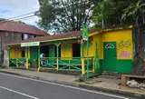 A yellow and green roadside bar with a shaded veranda and wooden railings.