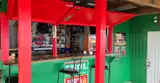 A local bar counter framed by bright red posts, green panels and shelves of drinks.