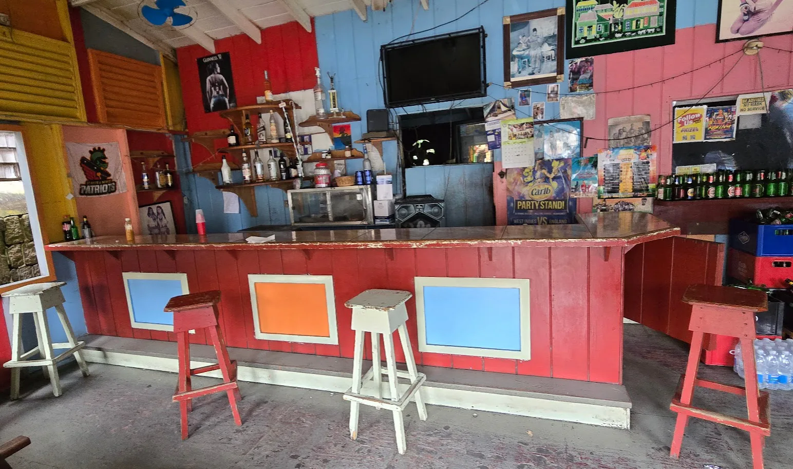 A colourful bar interior with red and white stools and bottles behind the counter.