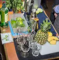 A cocktail-making station with pineapple, lime, mint, glasses and metal shakers.