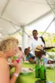 A smiling host visits guests as they enjoy food on the covered terrace at Carambola.