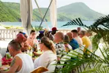 Guests dine together under a terrace canopy with St. Kitts’ green hills across the bay.