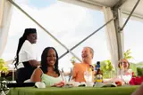 Guests smile together at a terrace table while a Carambola host stands beside them.