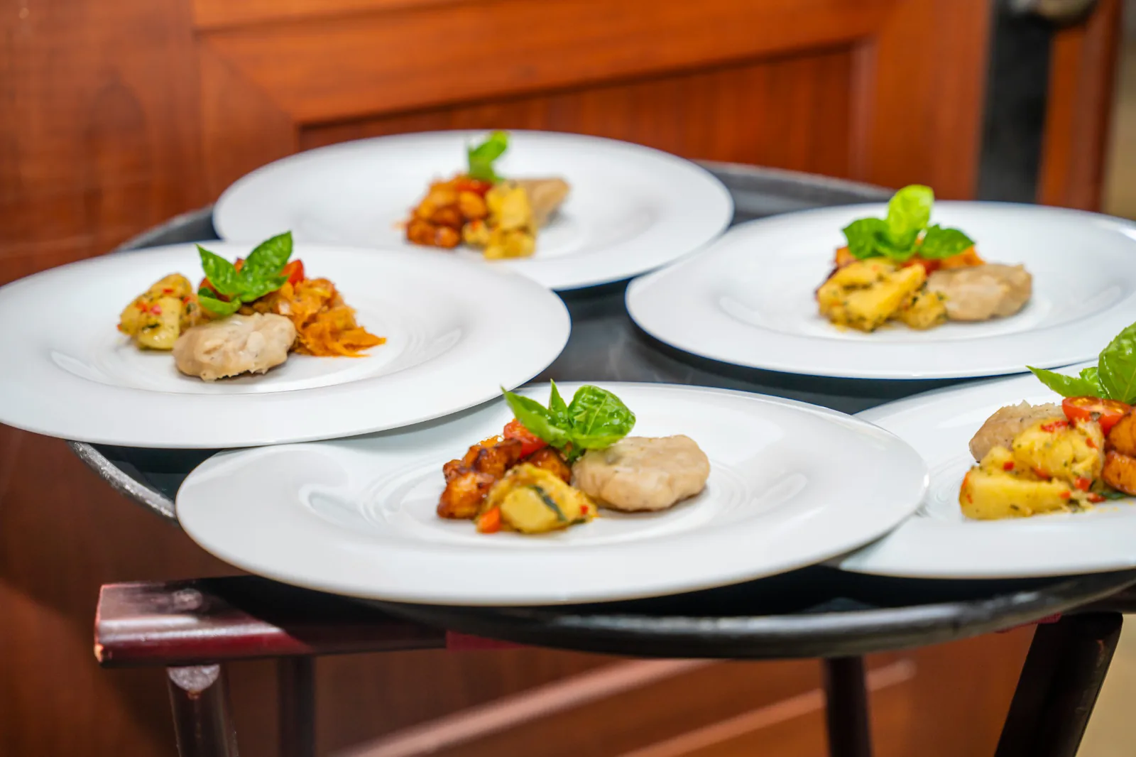 A selection of small plates garnished with greens, ready to be served at Carambola.