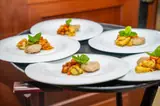 A selection of small plates garnished with greens, ready to be served at Carambola.