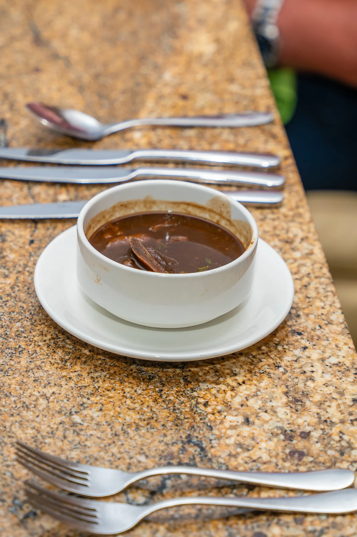 A white bowl of rich broth served on the dining table during the Carambola food tour.